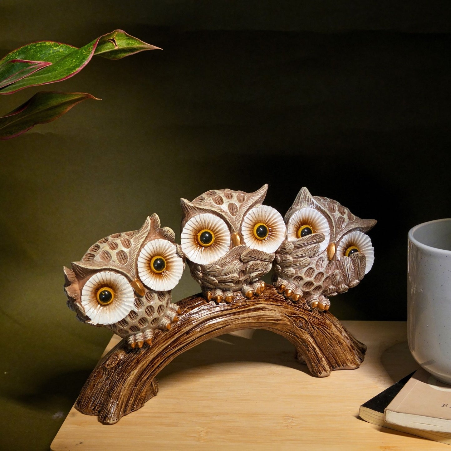 Decorative owl sculpture on a branch with a cup in the background