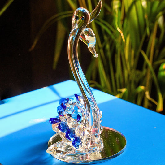 Crystal swan figurine with blue crystals on a reflective surface