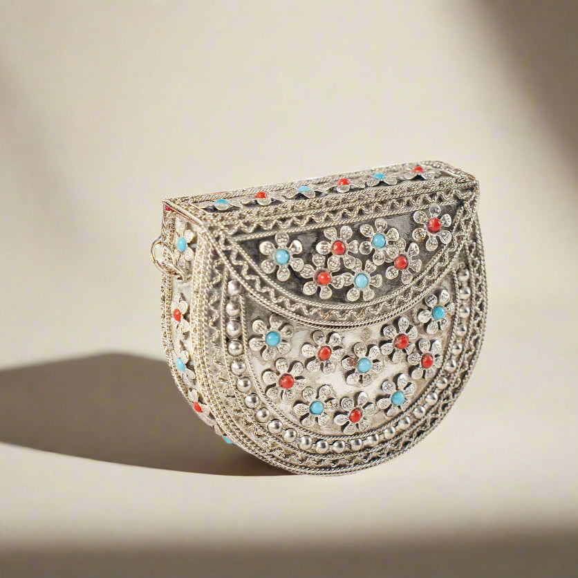 A small, decorative metal purse with intricate designs and colorful enamel details.