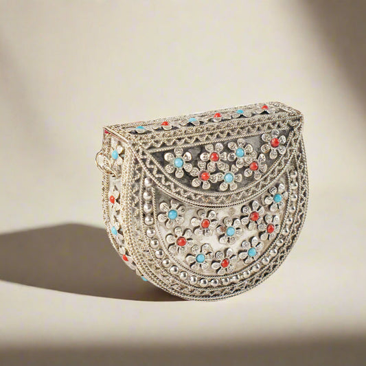 A small, decorative metal purse with intricate designs and colorful enamel details.