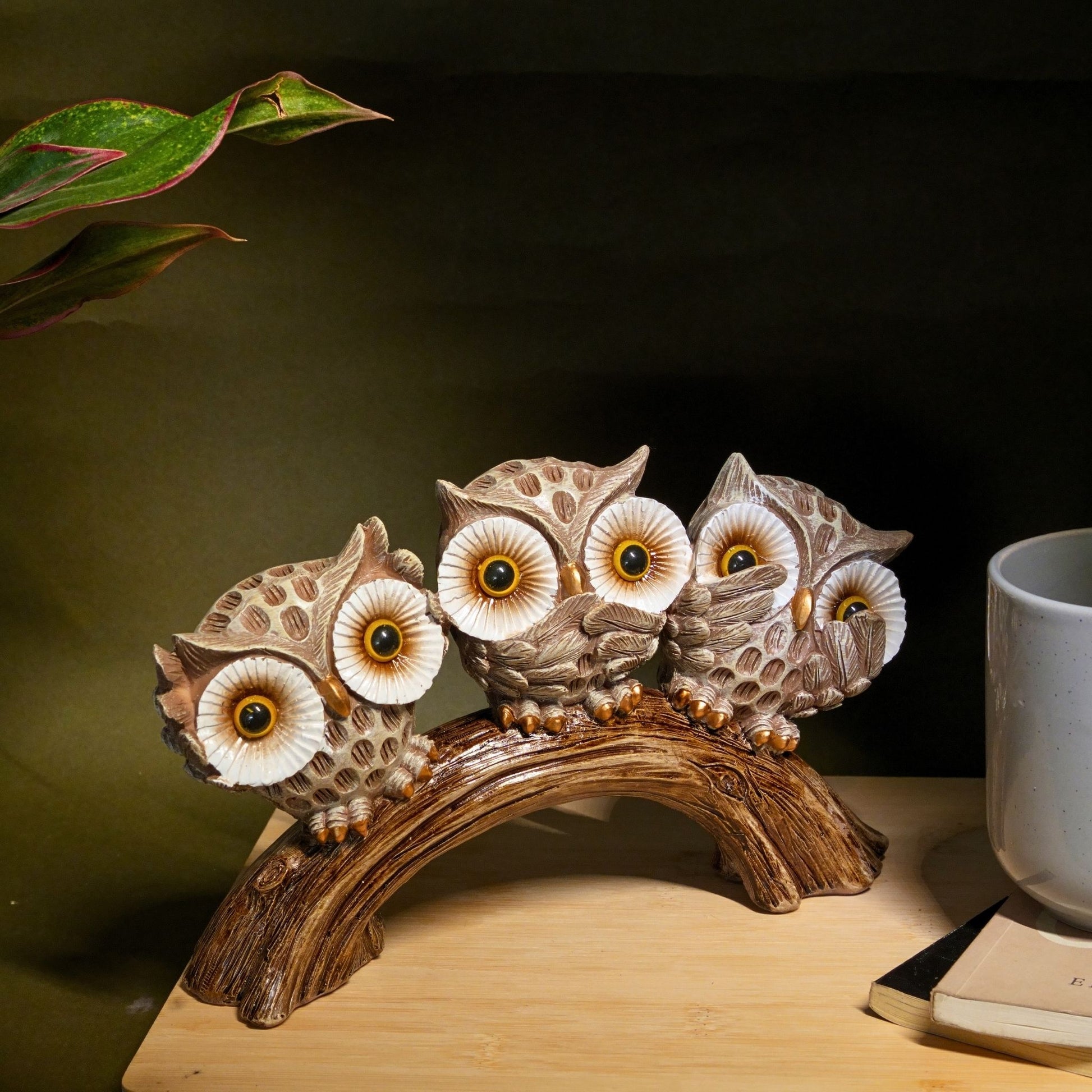 Decorative owl sculpture on a branch with a cup in the background